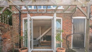 A brick house with a wooden porch, a sliding glass door, and a staircase leading to the upper floor.