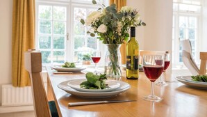 A dining table set with plates of food, wine glasses, and a vase of flowers.