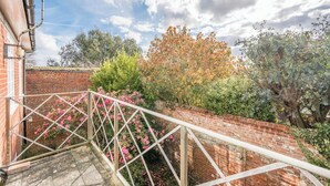A brick wall with a metal staircase leading to a balcony.