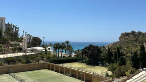 Una cancha de tenis con vistas al mar y un paisaje rocoso.