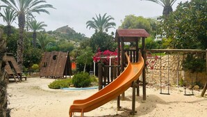 Un parque infantil con un tobogán, columpios y estructuras de juego de madera.
