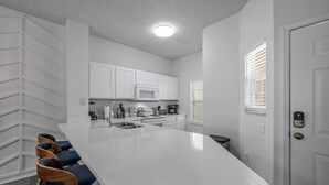 A modern kitchen with white cabinetry, a large island, and bar stools.