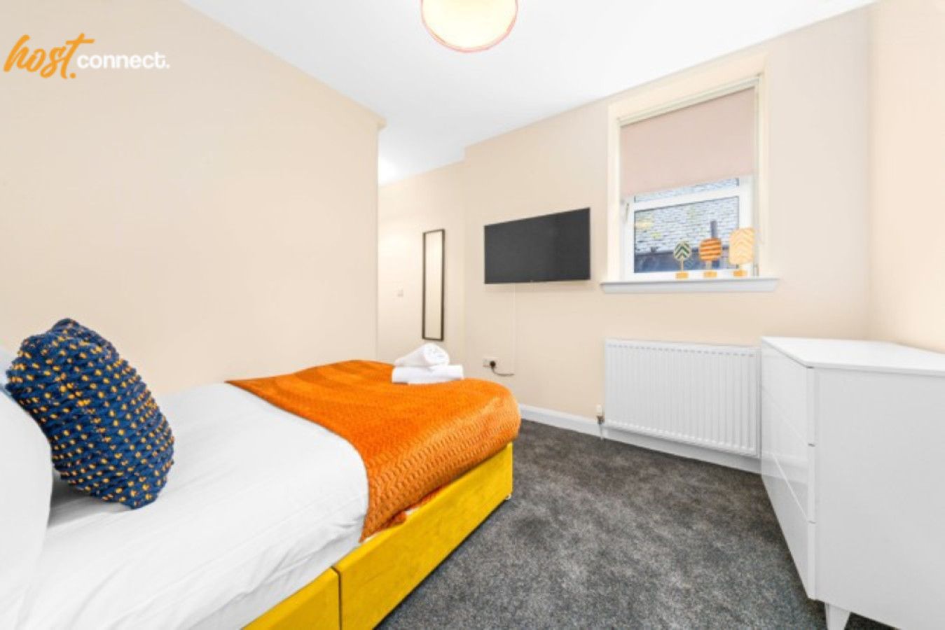 Ein Hotelzimmer mit Bett, Fenster mit Blick, weißem Heizkörper und Fernseher an der Wand.