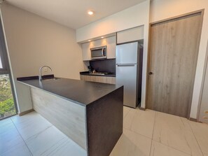 A modern kitchen with a central island, stainless steel appliances, and a sliding wooden door.