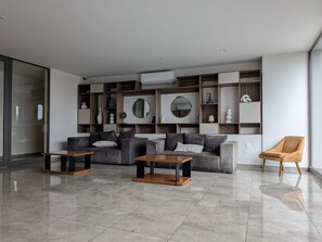 A modern living room with a sofa set, two coffee tables, and a single armchair.