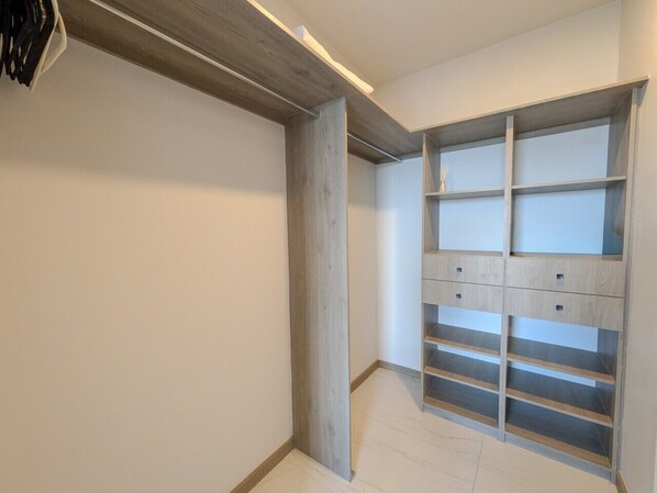 A room with a built-in wardrobe, a wooden beam ceiling, and a tiled floor.