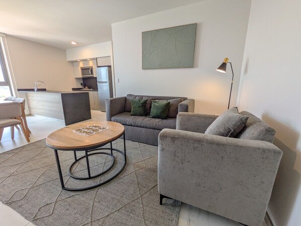 Una sala de estar moderna con un sofá gris, una mesa redonda de centro y un diseño minimalista.