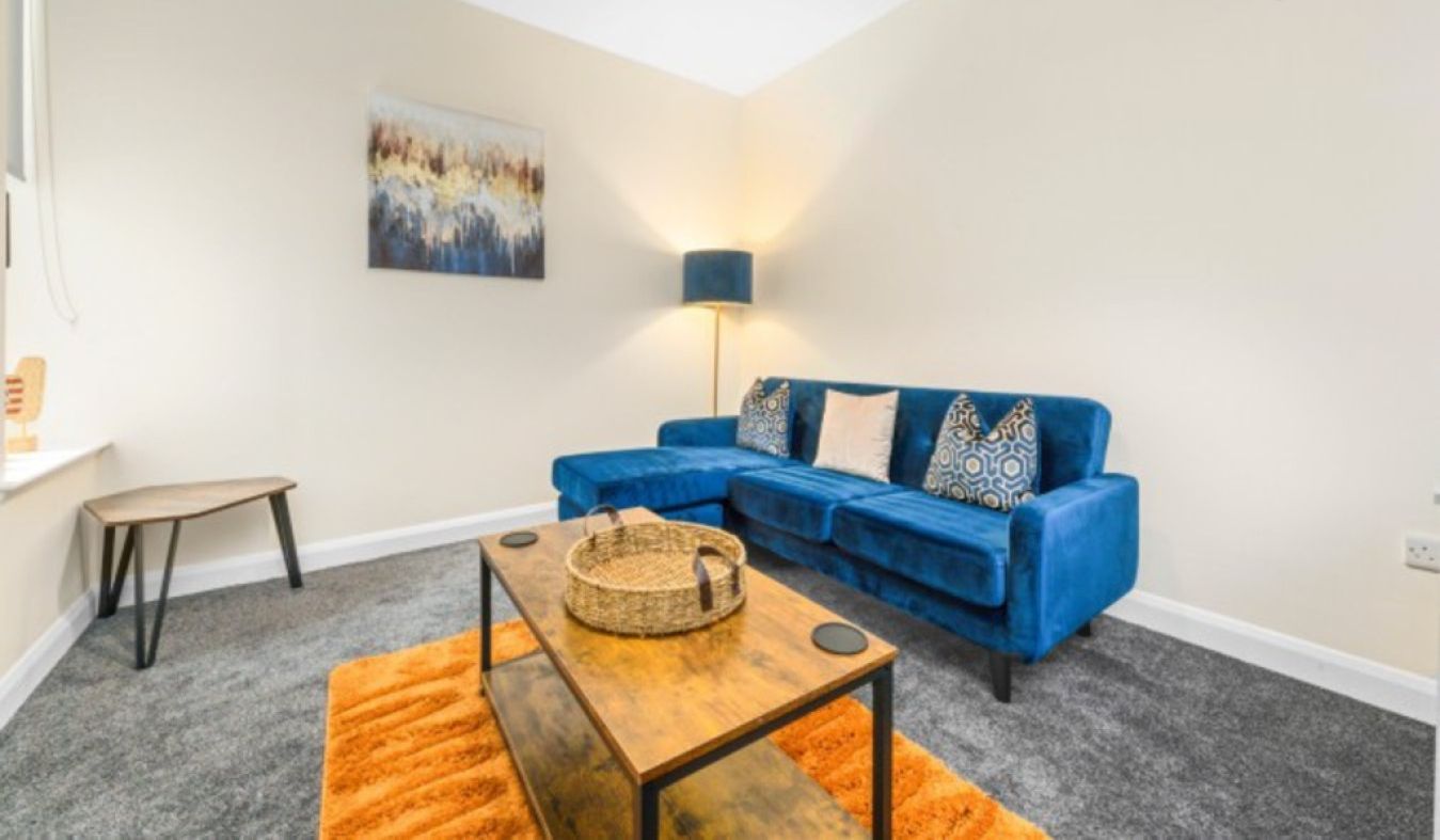 Ein modernes Wohnzimmer mit einem blauen Sofa, einem Holztisch und einer Stehlampe.
