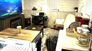 Una sala de estar acogedora con televisor de pantalla plana, chimenea, mesa de comedor y sofá confortable.