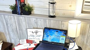 Una computadora portátil sobre un escritorio con papeles, un cartel de wifi y una lámpara.