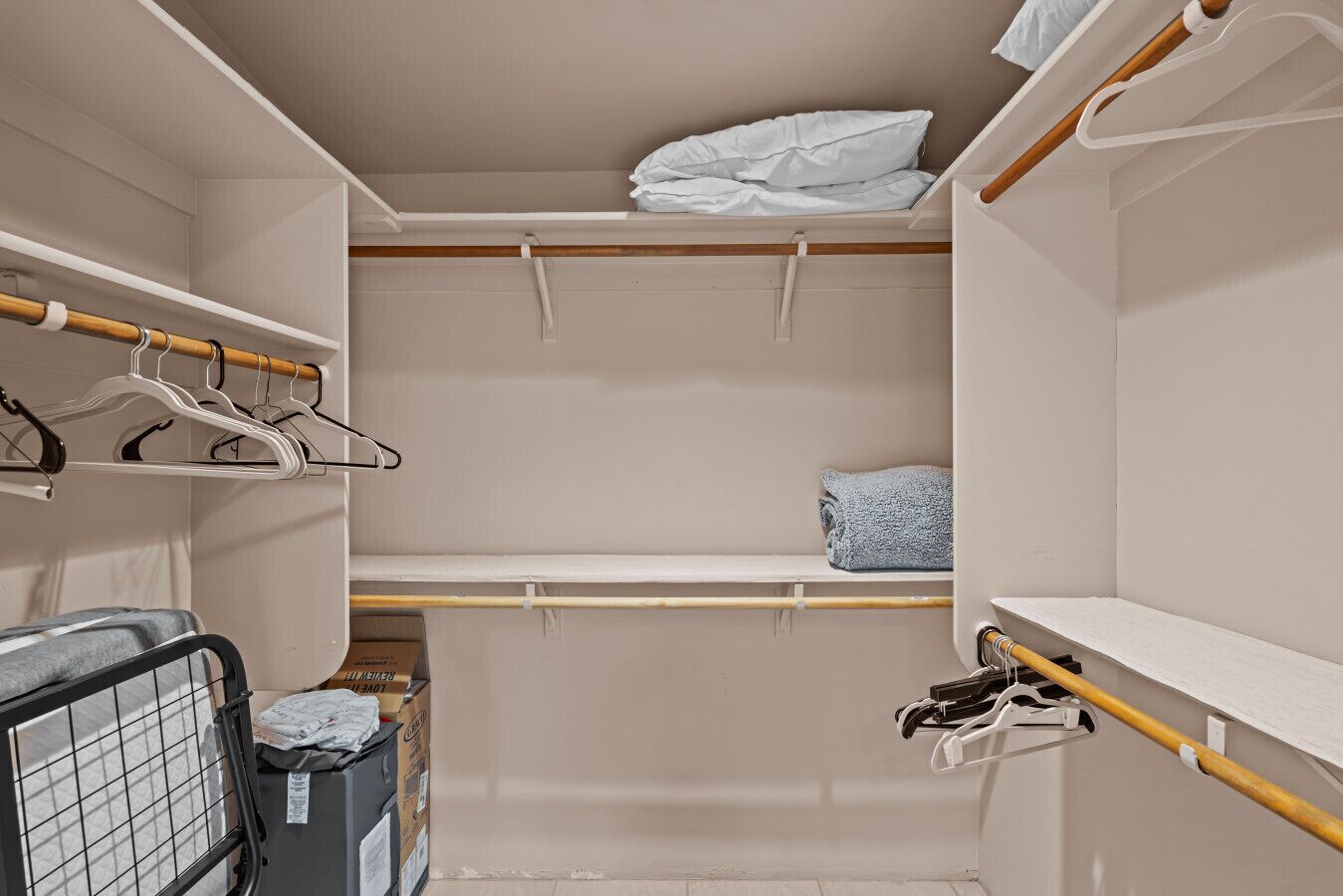 A walk-in closet with wooden rods, white hangers, and a blue towel.
