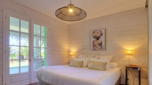 Ein Schlafzimmer mit einem großen Bett, zwei Nachttischlampen, einem Deckenventilator und einer Tür, die auf einen Balkon führt.