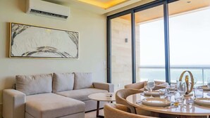 Una sala moderna con sofá, una mesa de comedor para dos personas y un ventanal con vistas.