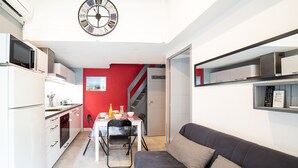 A compact living space with a kitchenette, dining area, and a sofa. - Notre Patio - Maisonette climatisée proche plage (Saint-Cyprien)