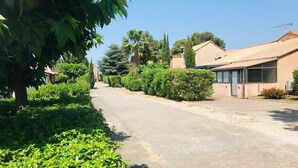 A residential street lined with houses, greenery, and a clear sky. - Notre Patio - Maisonette climatisée proche plage (Saint-Cyprien)