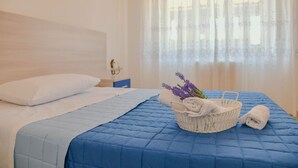 Una cama bien hecha con colcha azul, almohada blanca y cabecera blanca.