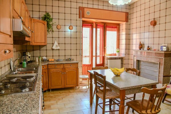 A kitchen with wooden cabinets, a granite countertop, a gas stove, and a dining table with chairs.
