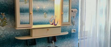 A bathroom with a large mirror, a sink, and a hairdryer on the wall.