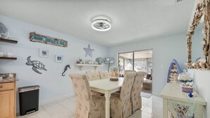 A dining area with a table and chairs, a trash bin, and decorative items on the walls.