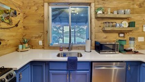 Una cocina con paredes de madera, una ventana, un fregadero, una estufa y armarios.