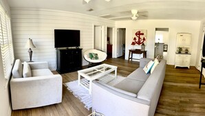 A living room with a sofa, armchair, coffee table, TV, and a decorative anchor wall piece.