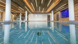Un'ampia piscina interna dal design moderno, con soffitto in legno e un cartello che riporta 'CHALET ALTITUDE'.
