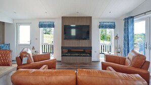 A modern living room with leather sofas, a flat-screen TV, and a fireplace. - 2 bedroom accommodation in Old Langho, Ribble Valley (Old Langho, Ribble Valley)