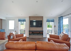 Ein modernes Wohnzimmer mit Ledersofas, einem Flachbildfernseher und einem Kamin.