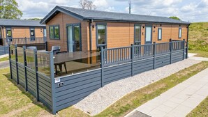 A modern cabin with a deck, large windows, and a gravel pathway. - 2 bedroom accommodation in Old Langho, Ribble Valley (Old Langho, Ribble Valley)