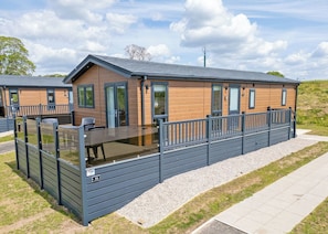 Une cabane moderne dotée d’une terrasse, de grandes fenêtres et d’un chemin en gravier.