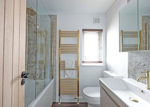 Un bagno con box doccia in vetro, un water, un lavandino e un portascopevoli.