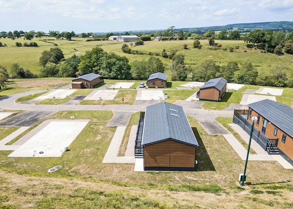 Il s’agit d’une propriété rurale comprenant plusieurs bâtiments en bois, un espace de stationnement et un grand champ ouvert.