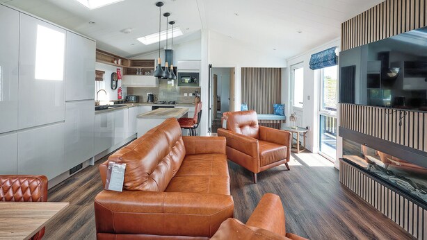 A modern kitchen with a central island, a dining area with leather sofas, and a large TV mounted on the wall. - 2 bedroom accommodation in Old Langho, Ribble Valley (Old Langho, Ribble Valley)