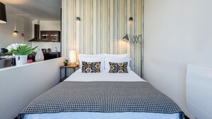 A modern hotel room with a large bed, striped wallpaper, and a view of the kitchen. - Charming Apartment with street-view in Porto (Oporto)