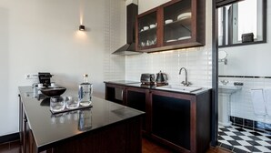 A modern kitchen with dark wooden cabinets, a black countertop, and a white tiled backsplash. - Charming Apartment with street-view in Porto (Oporto)
