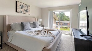 Ein Schlafzimmer mit einem großen Bett, einem Fenster mit Blick auf ein Gebäude und einem Gemälde an der Wand.