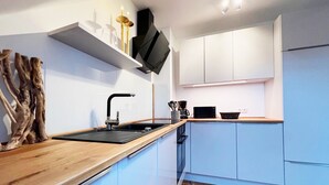 A modern kitchen with white cabinets, a wooden countertop, and a black range hood.