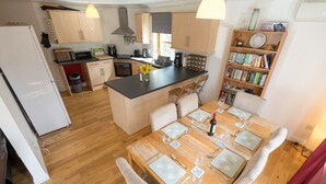 Eine moderne Küche mit Holzsäulen, einer zentralen Kochinsel und einem Essbereich mit einem Holztisch für sechs Personen.