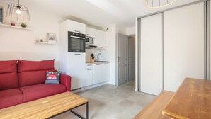 Un espacio habitable pequeño con kitchenette, un sofá rojo y una mesa de madera.
