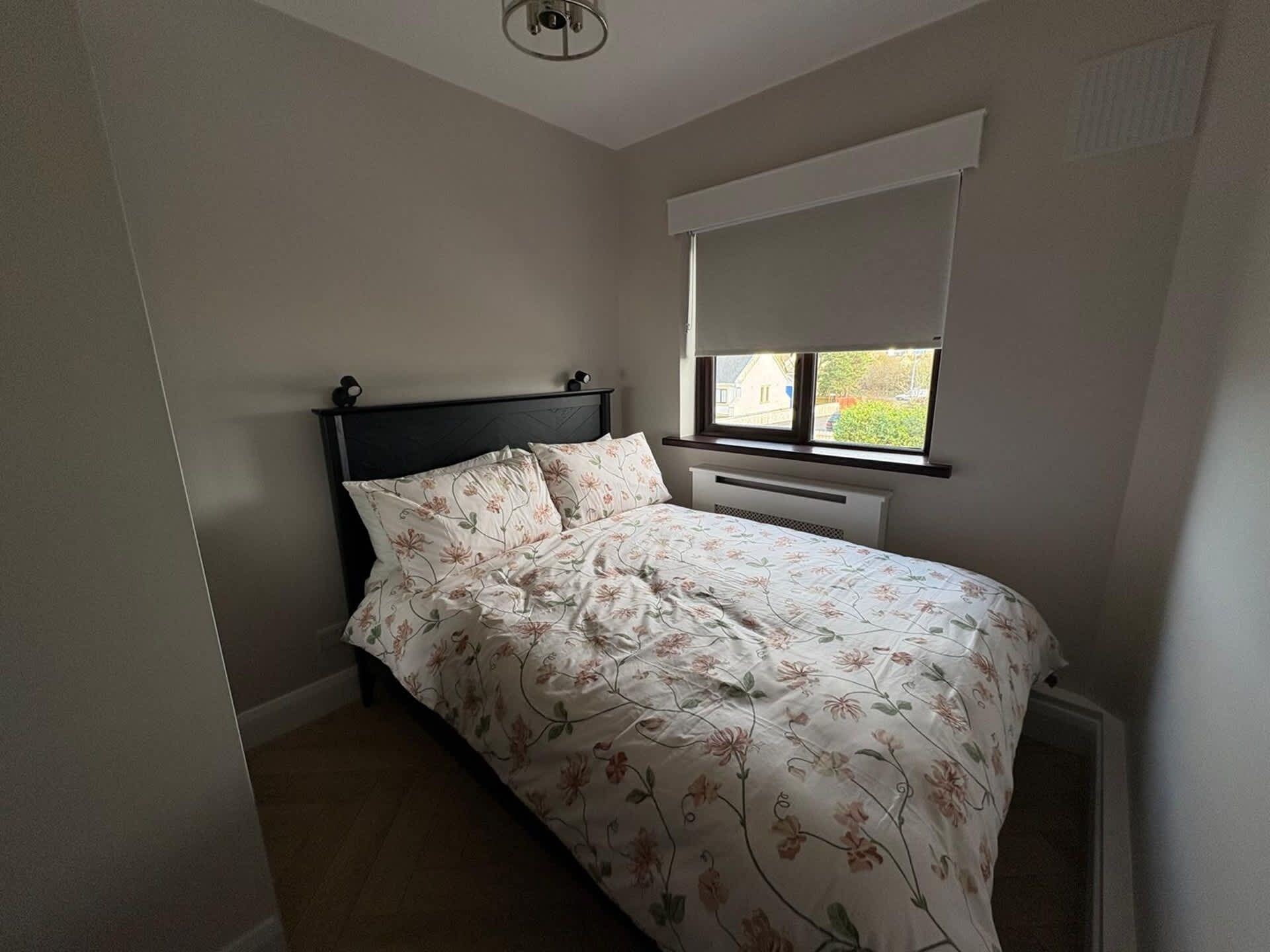 Une chambre à coucher avec un lit, une fenêtre avec un store et un radiateur.