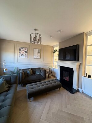 A living room with a fireplace, a sofa set, a television, and decorative wall art. - Gateway to Connemara (Oughterard)