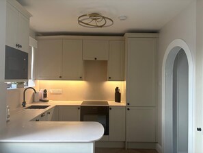 A compact kitchen with white cabinetry, a built-in oven, and a countertop with a sink.
