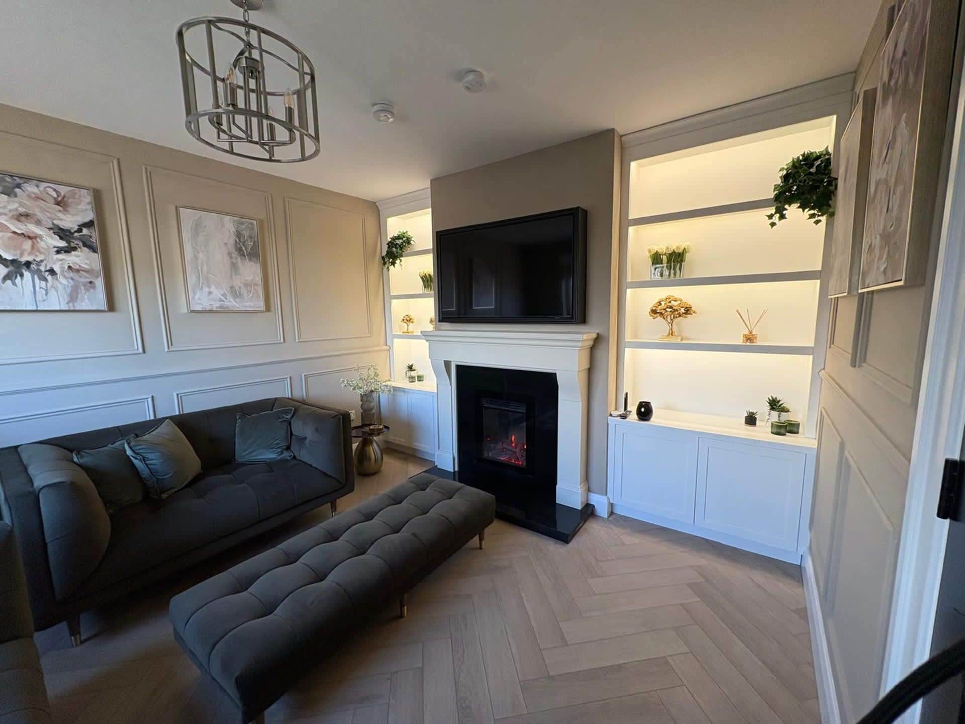 A living room with a sofa, a bench, a fireplace, a TV, and decorative shelves.