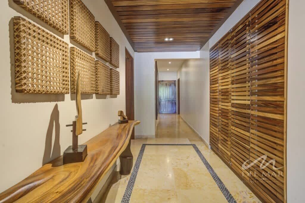 Un pasillo con un banco de madera, un revestimiento mural estampado y una pared con listones de madera.