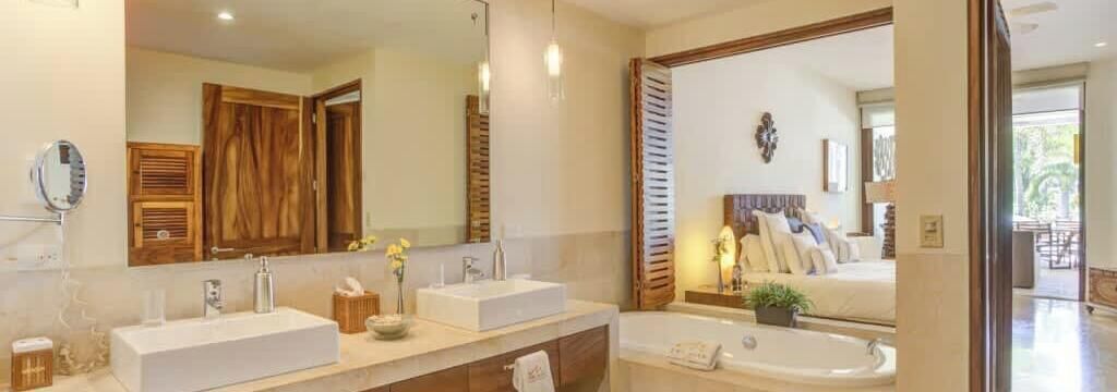 A modern bathroom with two sinks, a large mirror, and a bathtub.