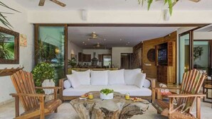 A modern living room with a white sofa, wooden chairs, and a central coffee table. - 3BR beach condo - pool, shore access & bay views (Cruz de Huanacaxtle)