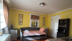 Un dormitorio con cama, refrigerador pequeño, microondas y armario.