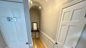Un pasillo con piso de madera, puertas blancas y un letrero que indica que es zona exclusiva para empleados.