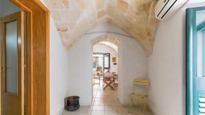 A narrow hallway with stone arches, a wooden door, and a blue-framed window. - La Casa delle Rondini by BarbarHouse (Torricella)