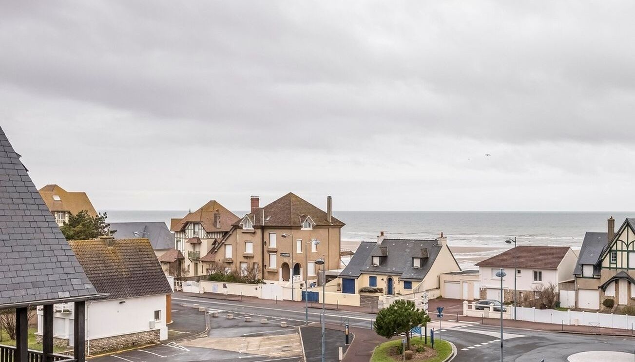 A coastal residential area with houses, a road, and a view of the sea.
